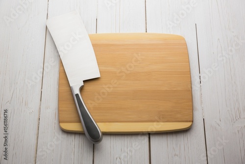Large knife and chopping board on wooden floor