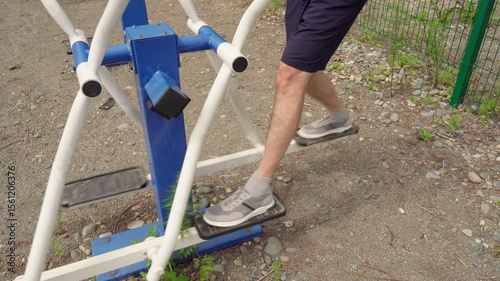 Exercise on a sports machine on a sports ground. Warm-up for leg muscles.