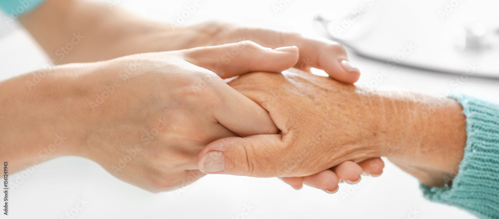 Fototapeta premium Doctor supporting elderly woman in clinic, closeup