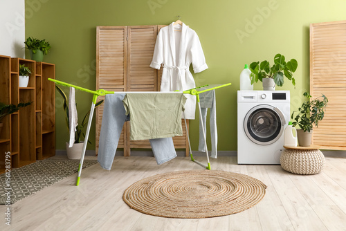 Valokuva Laundry room interior with washing machine and clothes on drying rack