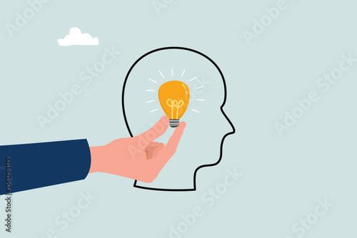 Inspiration concept. Hand holding luminous light bulb, putting in human brain.