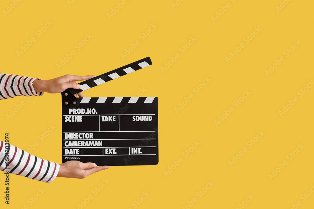Naklejka premium Female hands with movie clapper on yellow background