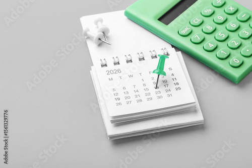 Calendar with green pin on date, closeup with calculator