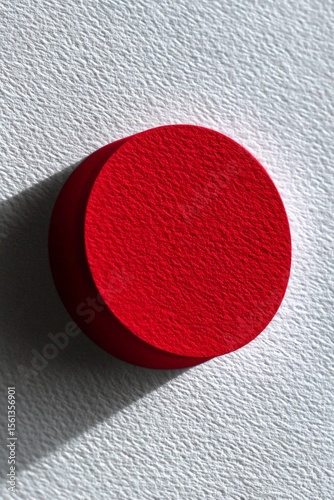 Minimalist red circle on textured white surface in natural light