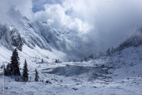 a snowy mountain range with a lake surrounded by snow covered mountains in the foreground and a cloudy sky in the background, with a few clouds in the foreground.