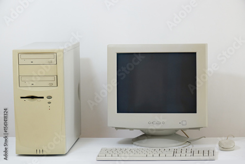 A classic desktop computer system from the past, featuring an old-fashioned CRT monitor, a beige tower unit, a keyboard, and a simple mouse, all isolated on a clean white surface.