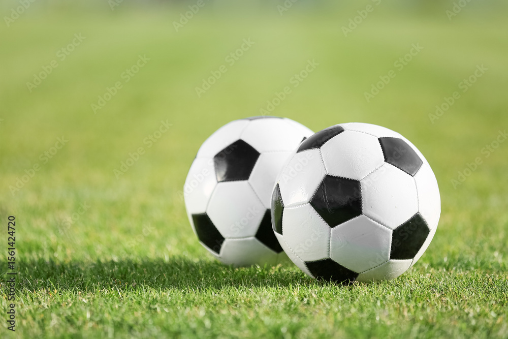 Obraz premium Soccer balls on green stadium grass, closeup