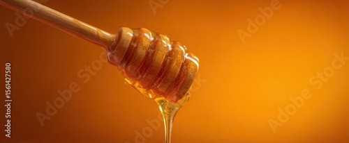 The honey dipper dripping golden syrup against a warm background.