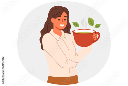 Woman drinks green loose leaf tea from large mug, enjoying bite of hot, soothing drink. Ceylon aromatic tea with mint and herbs in hand of business lady taking break while working or studying