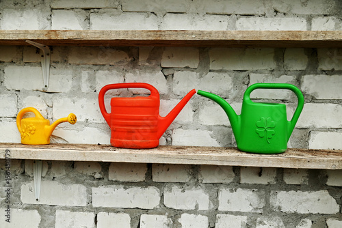 Watering cans on a brick shelf.