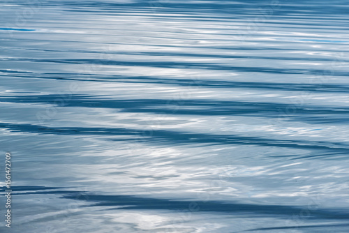 Rippling blue water surface reflecting light during midday at a tranquil lake