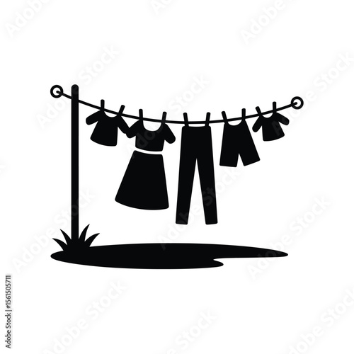 Black silhouette of clothes drying on a clothesline with a post and grass
