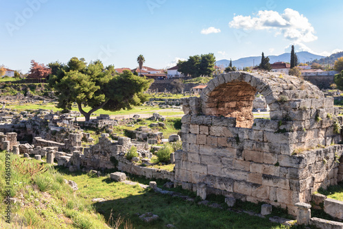 Ruins of ancient Corinth, Greece with stone arch and scattered remains under bright daylight