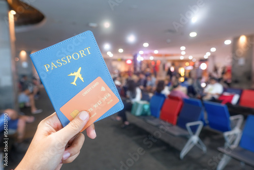 A person holds a blue passport wallet and a credit card in a busy airport lounge, with waiting passengers in the background. Perfect for travel, advertising, tourism, finance, and identity-themed
