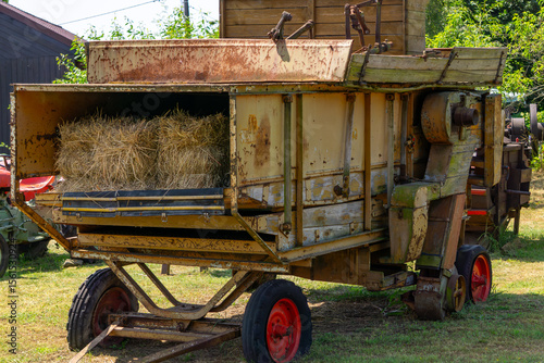 Valokuva Old agricultural threshing machine with straw bales inside, showing signs of rust and wear