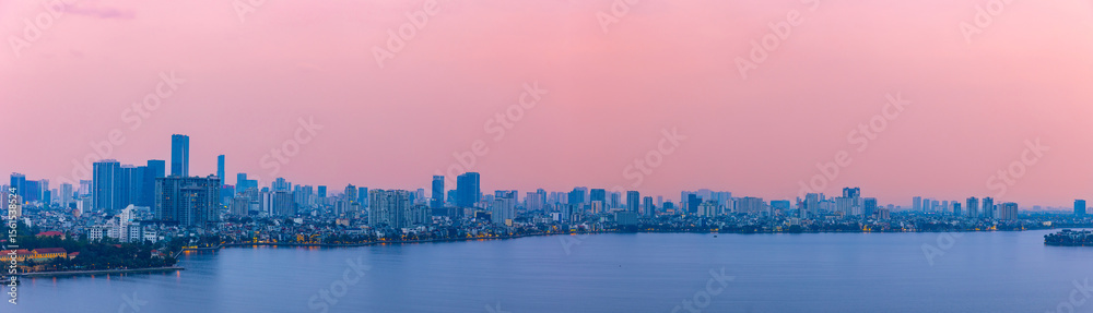 Naklejka premium Panoramic view of Hanoi skyline at dusk with pink sky and west lake reflections