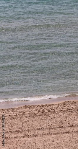 Portrait vertical footage of the lively Spanish city of Benidorm showing the Playa de Levante beach with local people and tourists on vacation relaxing sunbathing enjoying the sandy beach