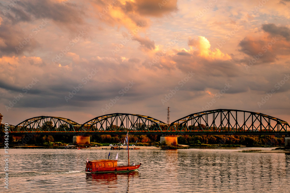 Obraz premium old wooden boat on the river, beauty clouds, sunset, bridge, beautiful view