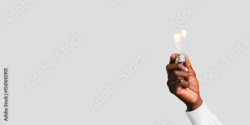 Hand holding light bulb on grey background  