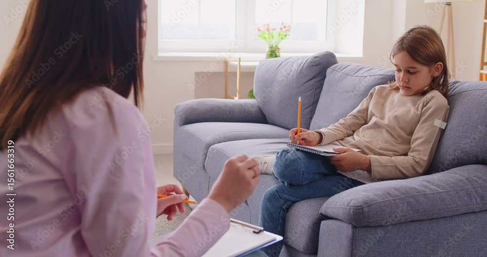 Female psychotherapist or school psychologist talking to little boy sitting on sofa during therapy session in office. Child answering questions in mental health questionnaire and and sharing thoughts. Female psychotherapist or school psychologist talking to little boy sitting on sofa during therapy session in office. Child answering questions in mental health questionnaire and and sharing thoughts.