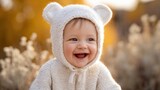 Adorable smiling baby girl wearing cozy knitted bear hat outdoors in autumn season.