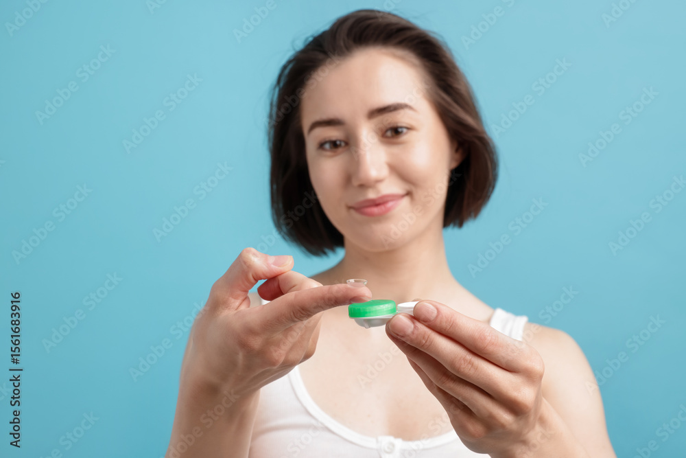 Woman with contact lens and case on light blue background, selective focus Woman with contact lens and case on light blue background, selective focus