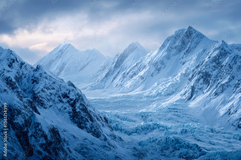 Obraz premium Majestic snow covered mountains and glacial valley under a dramatic cloudy sky