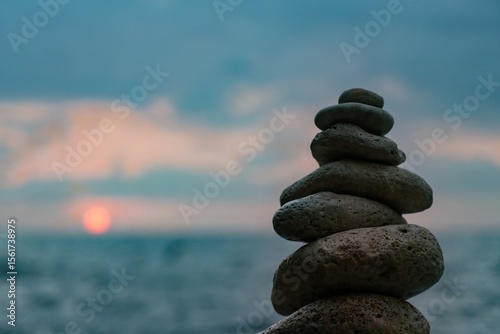 Canvas Print Stones Stacked Beach Sunset - A balanced pile of stones against a backdrop of a sunset over the ocean