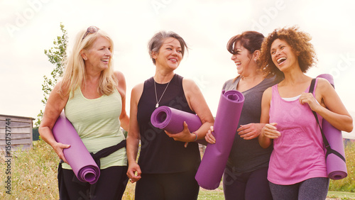 Group Of Mature Female Friends On Outdoor Yoga Retreat Walking Along Path Through Campsite