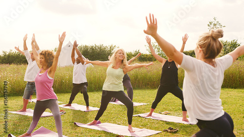 Female Teacher Leading Group Of Mature Men And Women In Class At Outdoor Yoga Retreat