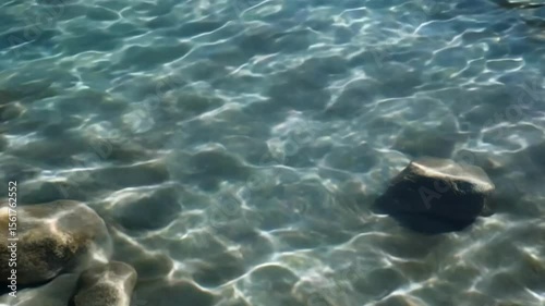 Crystal-clear water, rippled surface, with rocks beneath