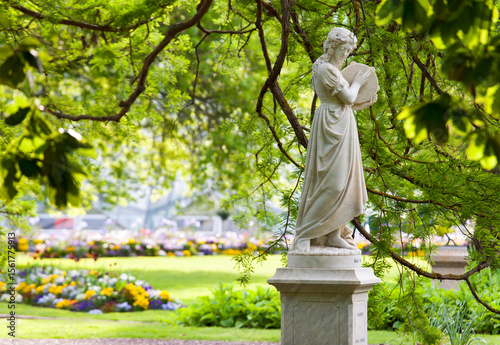 Statue in botanical gardens beneath green overhanging branches