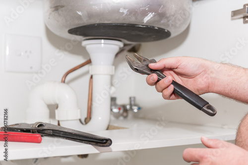 Plumber installing a sink and pipes with spanner