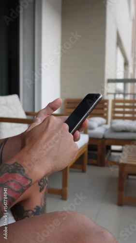 Scrolling social media feed on smartphone – vertical video. Hands holding smartphone and scrolling through social media app feed. Vertical 9:16 close-up of natural finger gestures, digital interaction