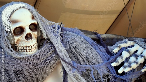 Halloween decoration featuring a terrifying monster draped in a purple cloth, hanging upside down and revealing a skeletal hand, adds a chilling touch to any spooky celebration