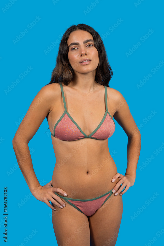 Naklejka premium Confident young woman posing in bikini on blue background