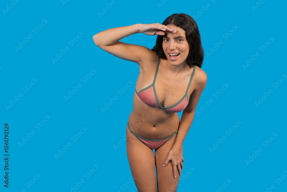 Obraz premium Young woman in bikini looking into the distance on blue background