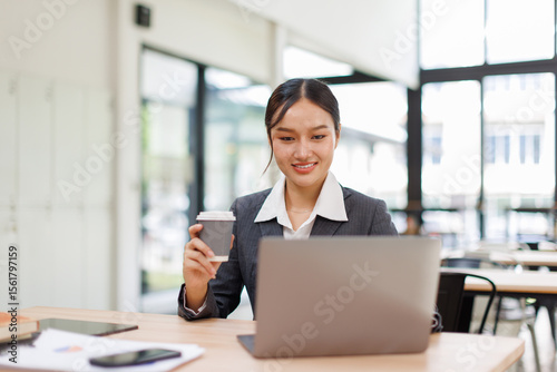 Wallpaper Mural Asian business woman accounting holding coffee cup using calculating income-expenditure and analyzing real estate investment data report Financial and tax systems concept.	 Torontodigital.ca