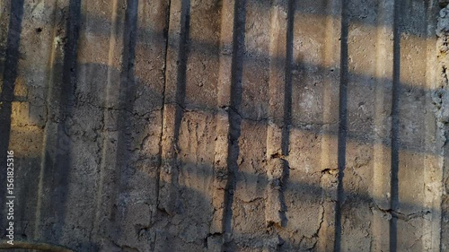 The surface of the concrete wall is textured with afternoon sunlight that shows the shadow of a person from behind the light of the setting sun.