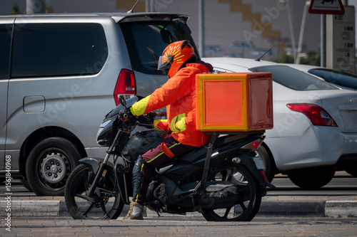 A food delivery courier is driving an order to a customer's home on a moped. takeaway food during quarantine. transport delivery of parcels at home. motorcycle rider with a big backpack