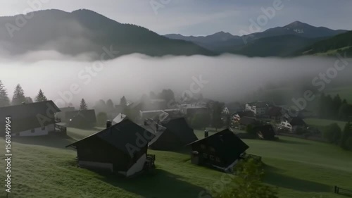Misty village nestled in a valley with mountain backdrop