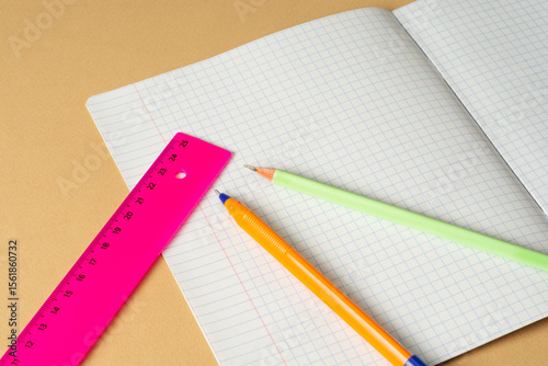 Thin notebook in a cage, pencil, pen and ruler. Stationery for students and schoolchildren. Copy space, macro