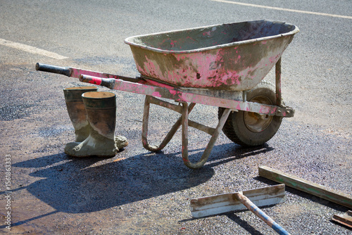 Wheelbarrow, tools and boots of concrete worker
