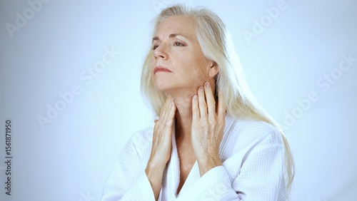 A mature woman with long, light-colored hair smiles happily while enjoying a spa treatment, showcasing a peaceful atmosphere with a white background.