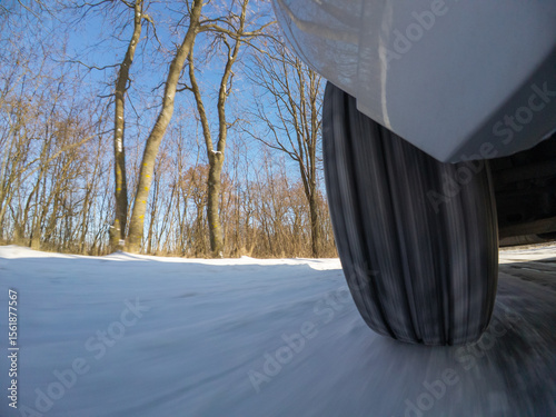 Car wheel on a snowy winter road. A moving wheel on a winter road, highlighting the difficulties and adaptation to harsh weather conditions during travel