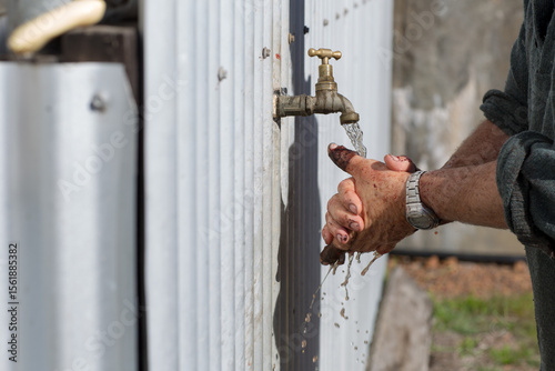 Washing dirty hands under a tap outside