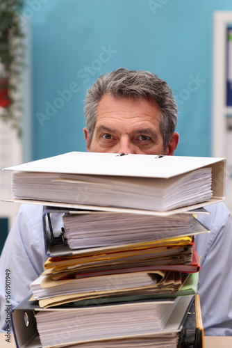 Office worker looks over a stack of files, looks concentrated