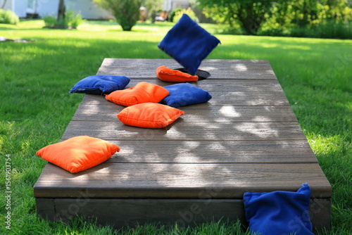 Blue cornhole bag in midair, about to join orange bags on a cornhole board