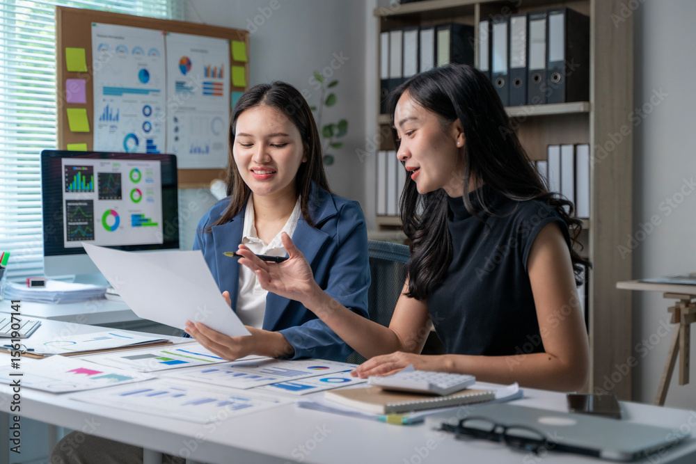 Obraz premium Two women are sitting at a desk with a white board behind them