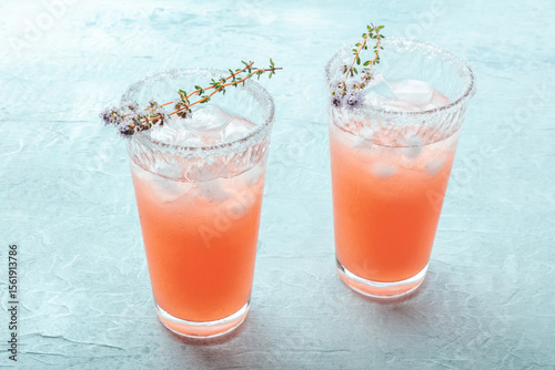 Salty Dog cocktail with fresh grapefruit juice, lime juice, and thyme, served with ice in a Collins glass